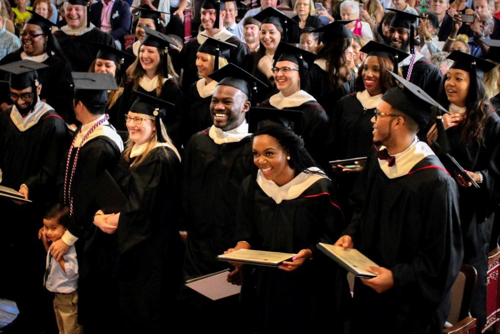 Graduates smile as a group after receiving their degrees