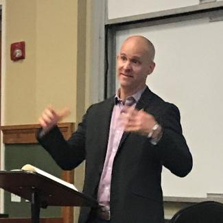 Luke Dittrich gives lecture at podium in an MLC classroom