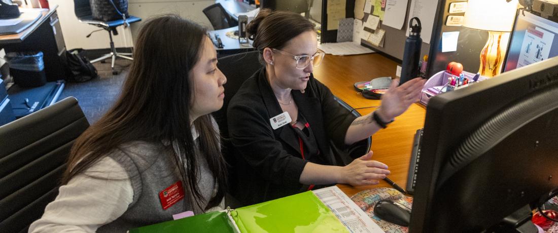 Student and staff member view a computer screen while engaged in discussion 