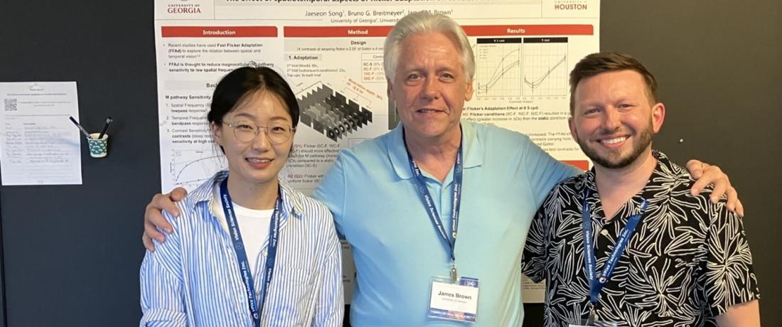 Dr. Brown standing between his students, Jaeseon Song and Ralph Hale, in front of their poster presentation, titled "the effect of spatiotemporal aspects of flicker adaptation on contrast discrimination," at an academic conference