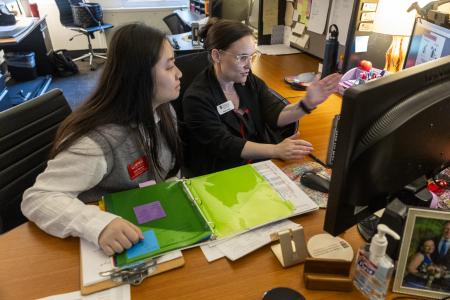Student and staff member view a computer screen while engaged in discussion 